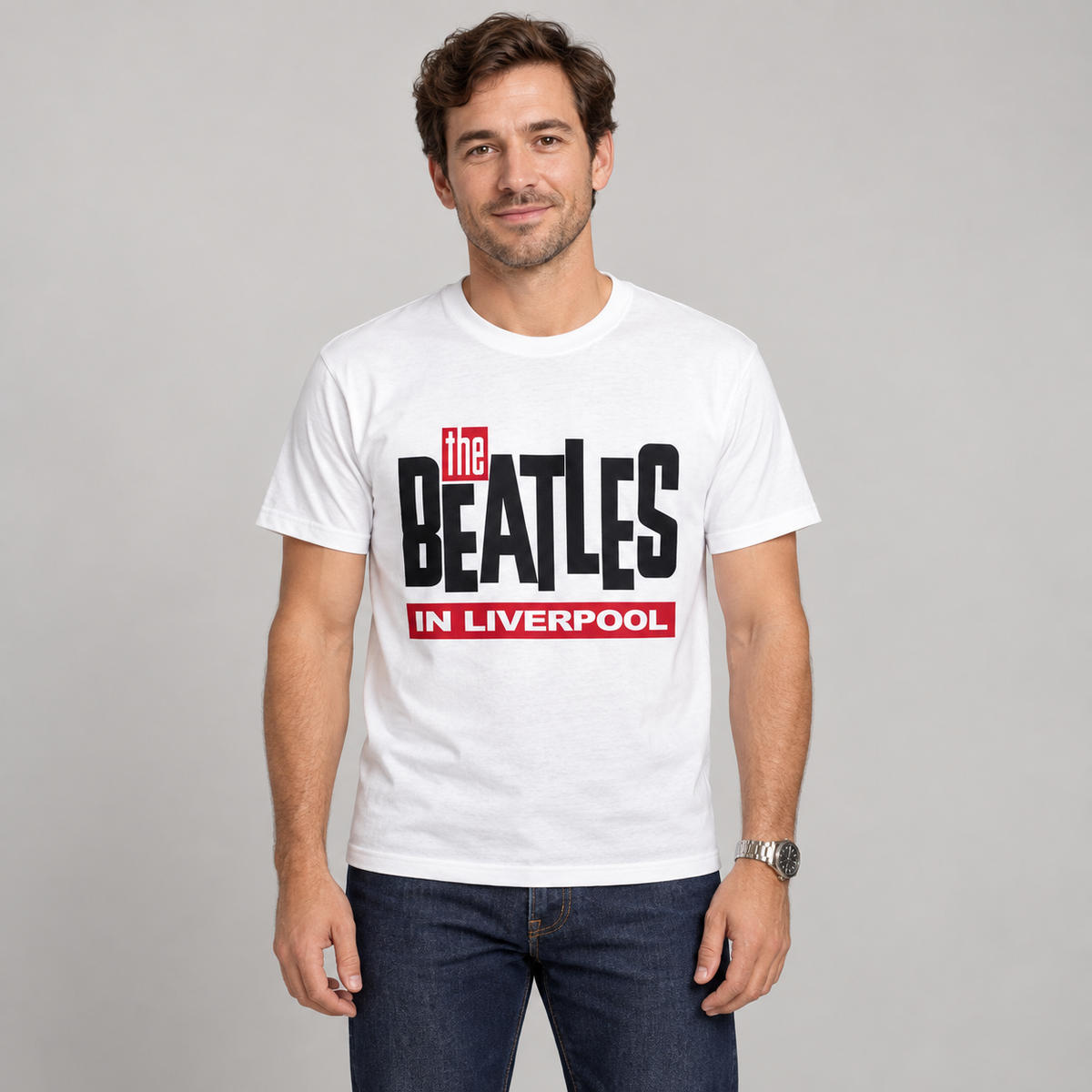Man wearing the white The Beatles in Liverpool T-shirt with black and red lettering in a studio.