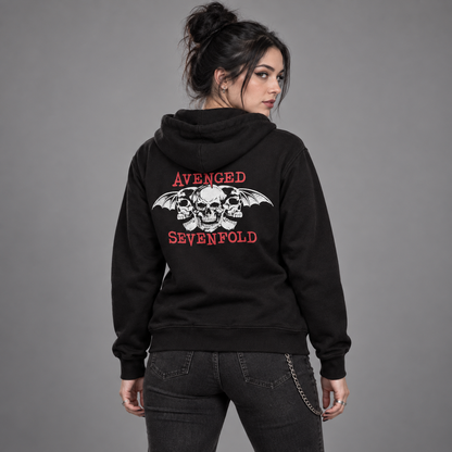 Studio back view of a woman wearing the black Avenged Sevenfold Dead Head hoodie, showing red band lettering and white skull-and-wings artwork.