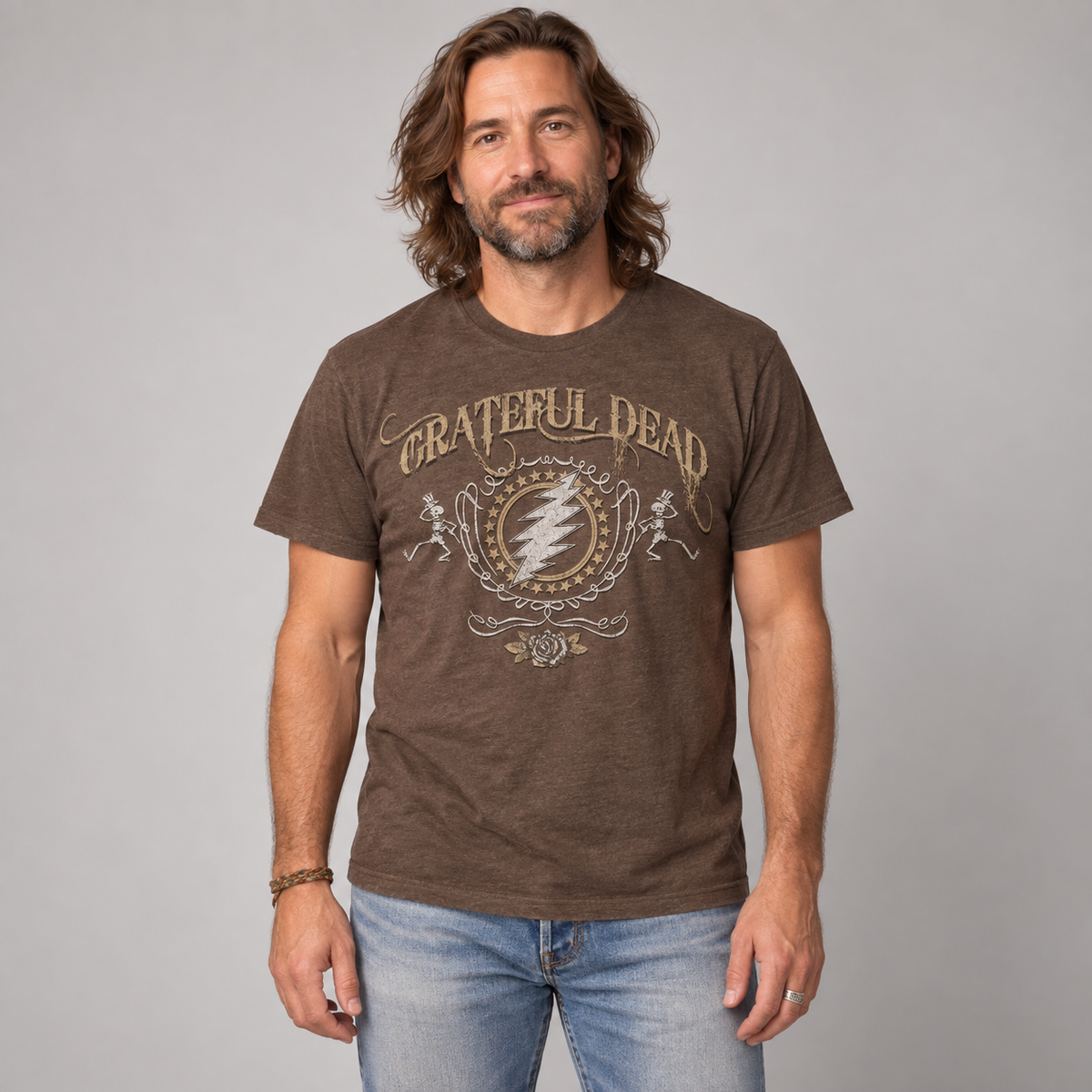Studio photo of a man wearing the brown Grateful Dead Bolt T-shirt, showing vintage lightning bolt, skeleton and rose artwork.