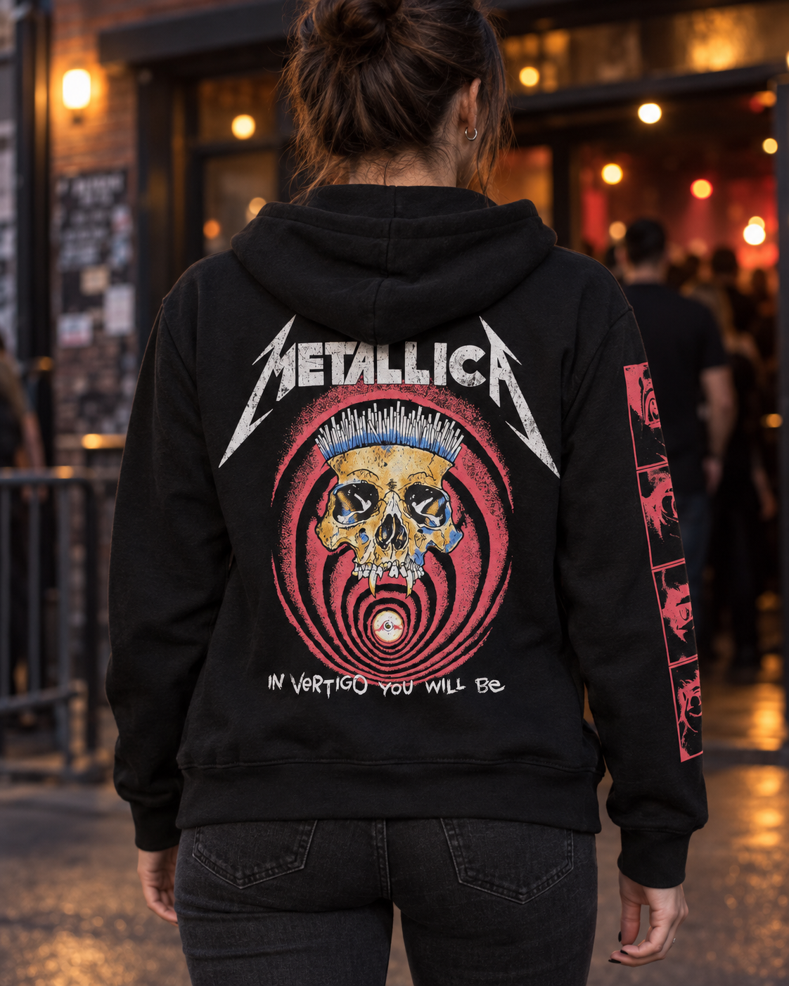 Back lifestyle view of the black Metallica In Vertigo hoodie outside a music venue, showing the skull and red vortex artwork.