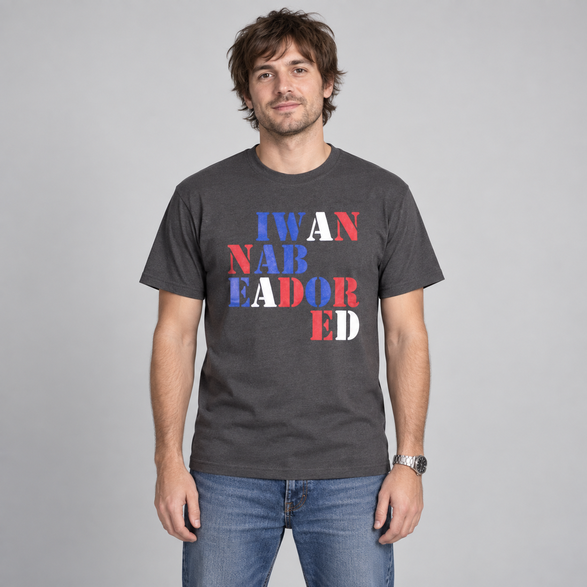 Man wearing the charcoal Stone Roses Adored T-shirt with red, white and blue stencil lettering in a studio.