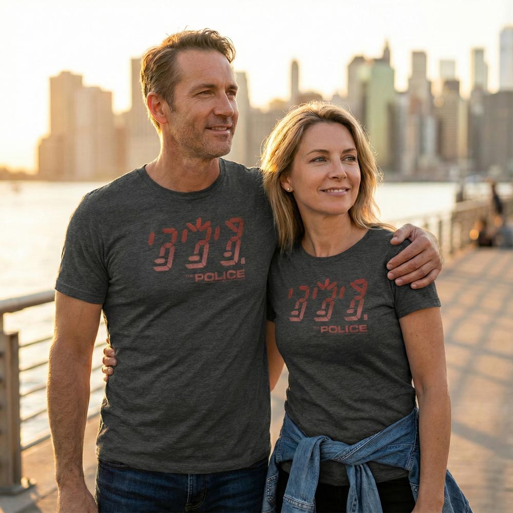 Man and woman wearing matching The Police t-shirts with a city skyline in the background.