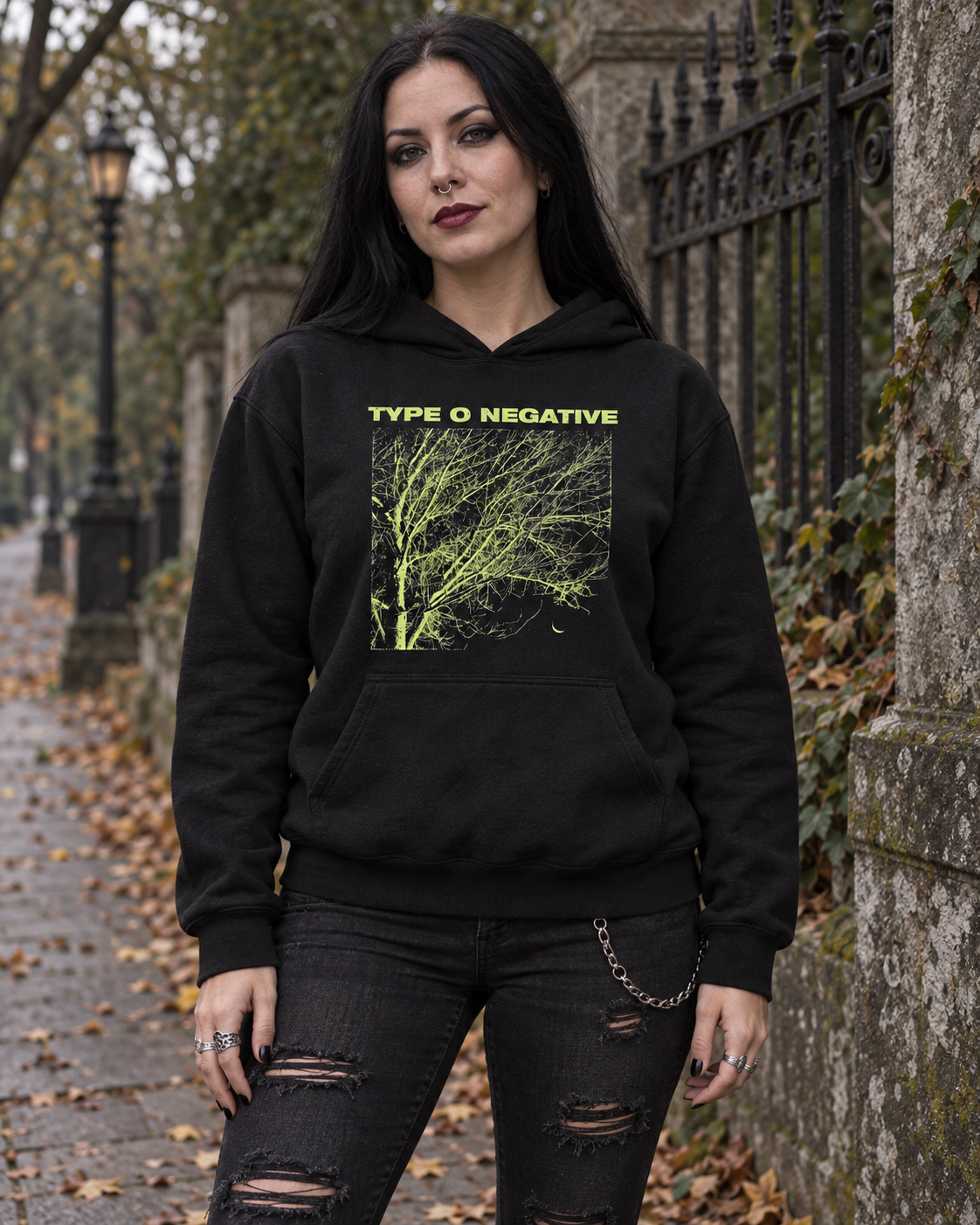 Woman wearing the black Type O Negative Tree pullover hoodie on an autumn street, showing the green front artwork.