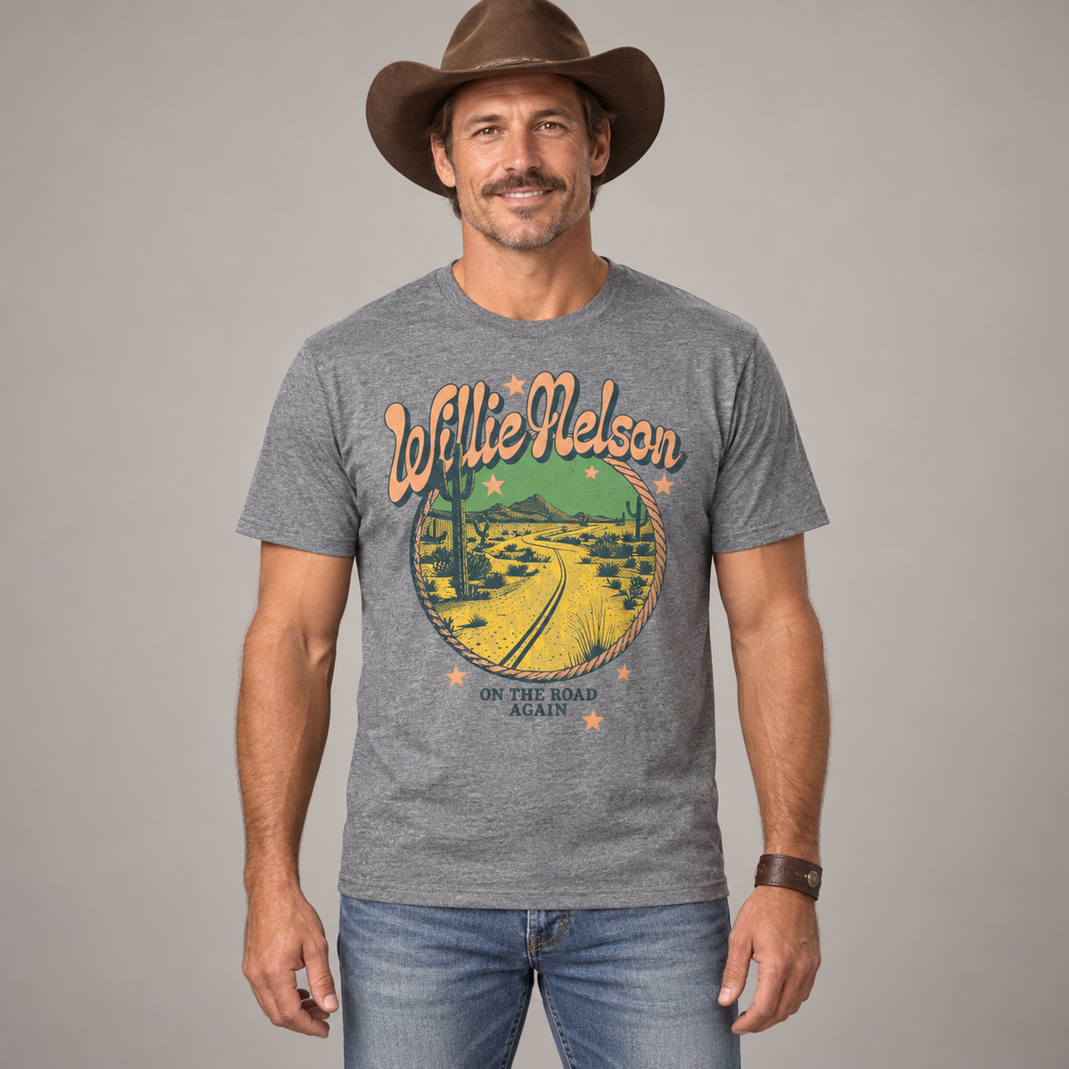 Man in country styling wearing the heather-grey Willie Nelson On the Road Again T-shirt in a studio.