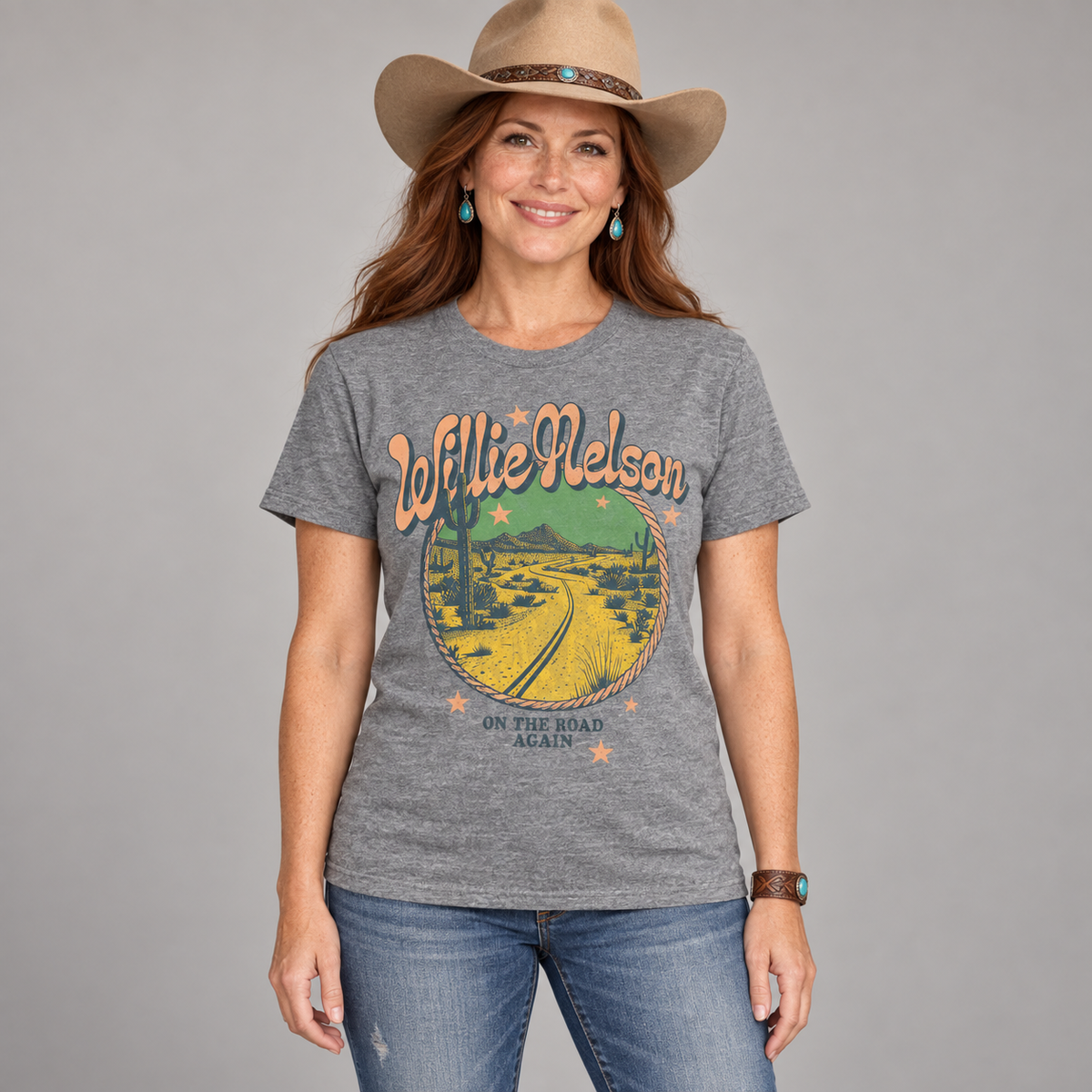 Woman in country styling wearing the heather-grey Willie Nelson On the Road Again T-shirt in a studio.